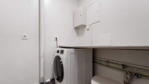 Una lavanderia spaziale con lavatrice, un WC e un armadietto sopra il lavandino.