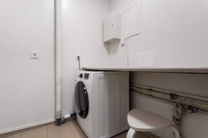 A compact laundry room with a washing machine, a toilet, and a cabinet above the sink. - Njálsgata Apartments by Heimaleiga (Reykjavík)
