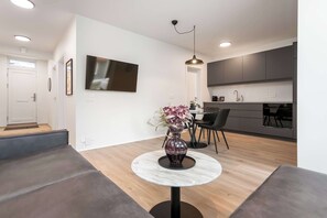 A modern living room with a round marble table, a vase with flowers, a sofa, a dining area with chairs, and a kitchen with grey cabinets. - Njálsgata Apartments by Heimaleiga (Reykjavík)