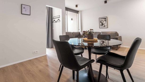 Un'elegante sala da pranzo moderna con un tavolo rotondo, sedie nere e un design minimalista.