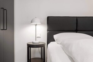 A modern hotel room with a bed, a bedside table with a lamp, and a wardrobe. - Njálsgata Apartments by Heimaleiga (Reykjavík)
