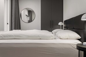 A modern bedroom with a bed, a round mirror, a wardrobe, and a bedside lamp. - Njálsgata Apartments by Heimaleiga (Reykjavík)