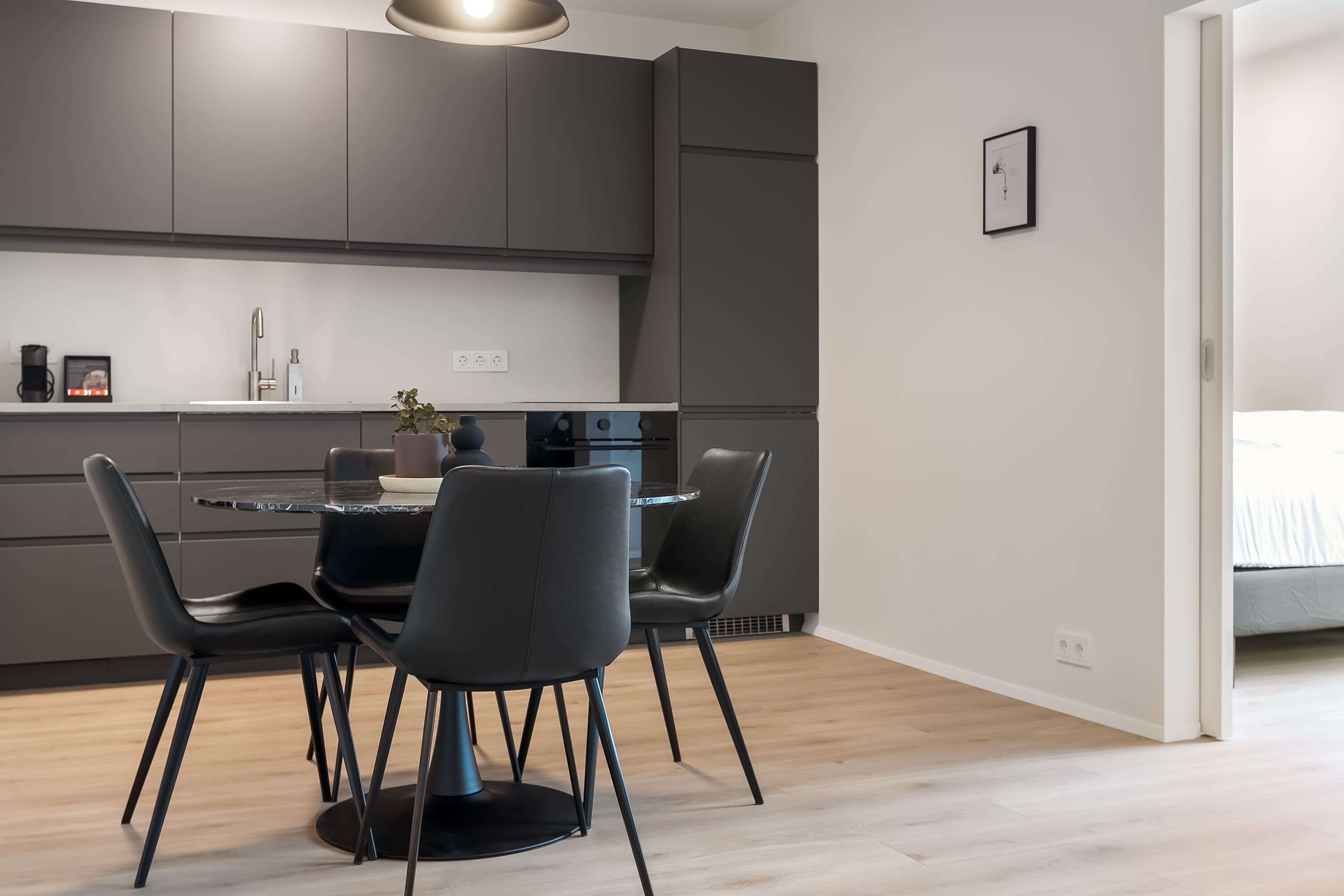 Une cuisine moderne avec des meubles de rangement aux couleurs sombres, une table de salle à manger ronde et quatre chaises.