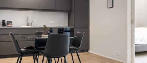 Une cuisine moderne avec des meubles de rangement aux couleurs sombres, une table de salle à manger ronde et quatre chaises.