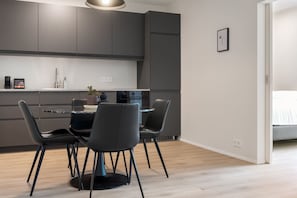 Une cuisine moderne avec des meubles de rangement aux couleurs sombres, une table de salle à manger ronde et quatre chaises.