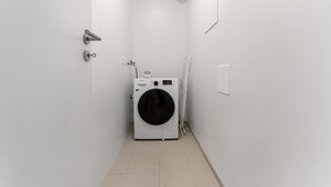 Een wasserij met een wasmachine, een deur en een wandlamp.