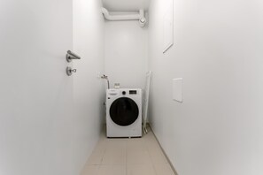 Ein Waschraum mit Waschmaschine, einer Tür und einer Wandleuchte.
