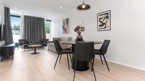 Een moderne woonkamer met een eethoek, grote ramen en kunstwerken aan de wanden.