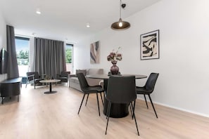 Ein modernes Wohnzimmer mit Essbereich, großen Fenstern und Kunstwerken an den Wänden.