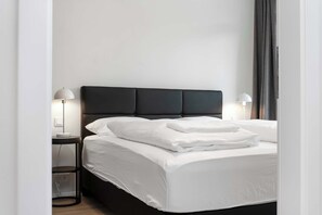 A neatly made bed with white linens and pillows, a dark headboard, and two bedside lamps on either side. - Njálsgata Charming Apartment by Heimaleiga (Reykjavík)