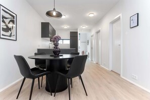 A modern dining area with a round table, four chairs, and a vase of flowers. - Njálsgata Charming Apartment by Heimaleiga (Reykjavík)