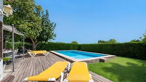A wooden deck with two yellow lounge chairs, a swimming pool, and a well-maintained lawn. - Villa Provenza with Private Pool, Terrace, A/C & Wi-Fi (Las Palmeras)