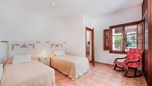 A bedroom with two beds, a wooden rocking chair, and a window with a view. - Villa Provenza with Private Pool, Terrace, A/C & Wi-Fi (Las Palmeras)