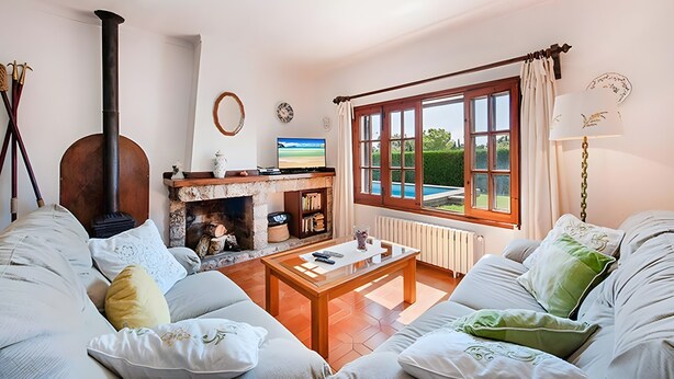 A cozy living room with a fireplace, a sofa set, a coffee table, and a large window with curtains. - Villa Provenza with Private Pool, Terrace, A/C & Wi-Fi (Las Palmeras)