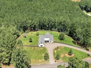 A large, single-story house with a fenced yard, surrounded by dense forest. - Roxies Retreat (Ball Ground)