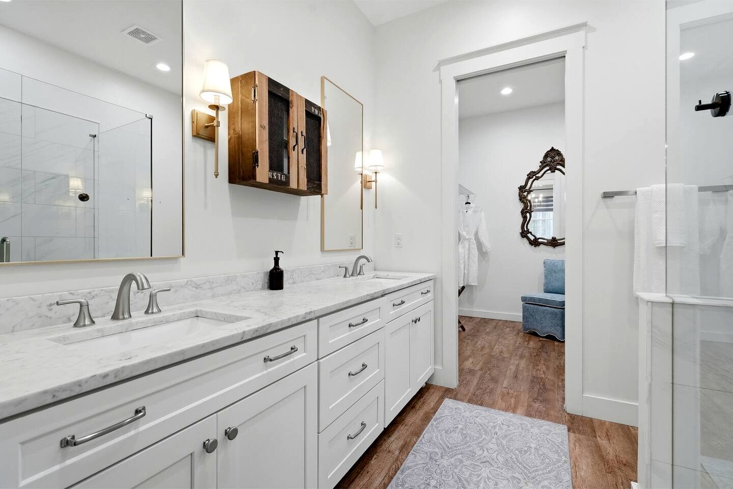 A modern bathroom with two sinks, a large mirror, and a wooden cabinet above the mirror.