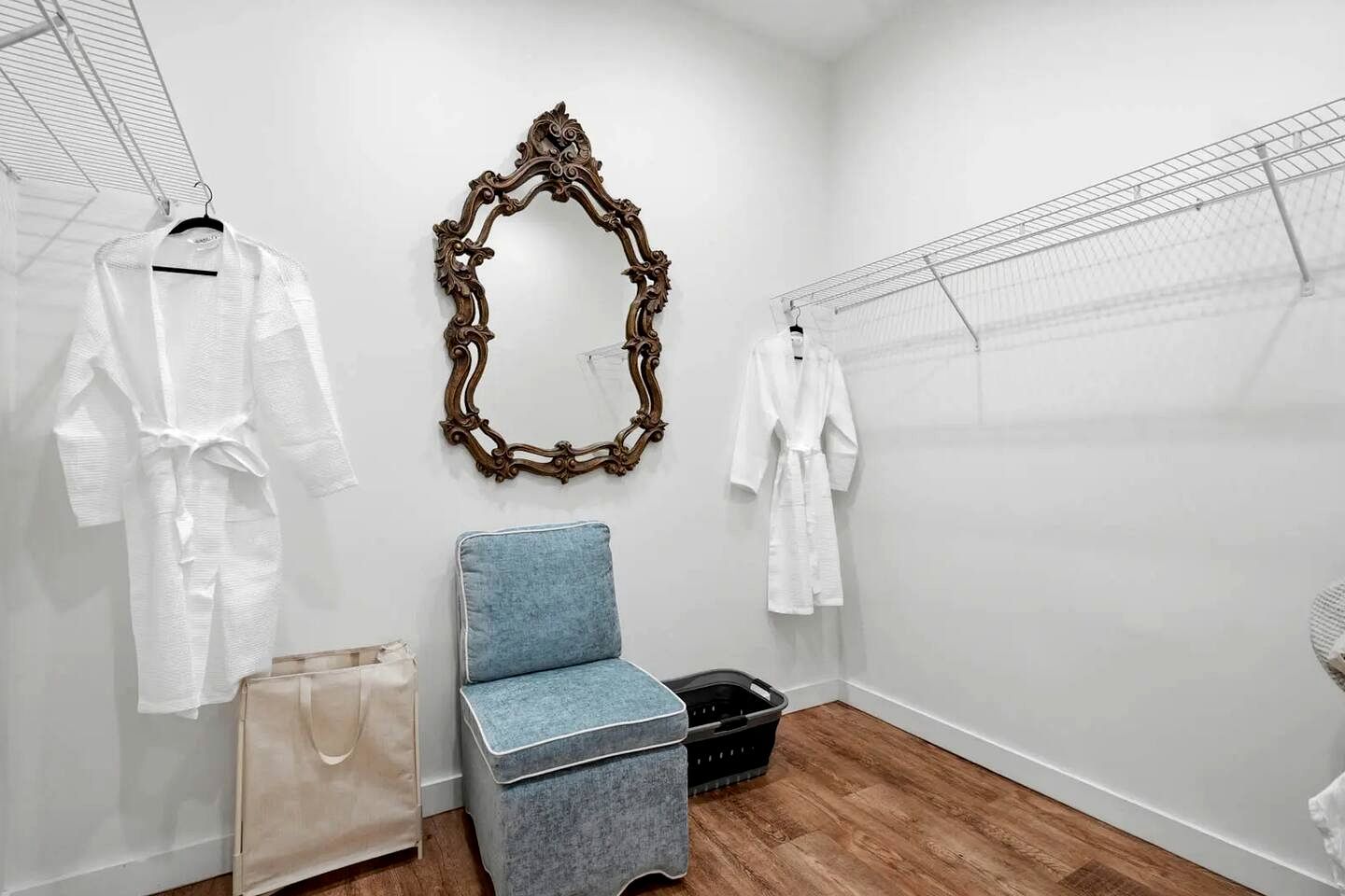 Une pièce avec un miroir, une chaise et un portant sur lequel sont suspendus des vêtements.