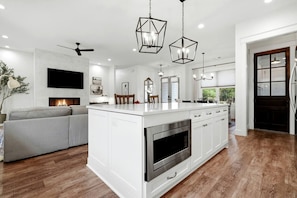 A modern kitchen with a central island, built-in oven, and pendant lighting. - Roxies Retreat (Ball Ground)