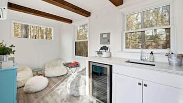 Une cuisine moderne avec des meubles blancs, un lave-vaisselle intégré et une grande fenêtre donnant sur la forêt.