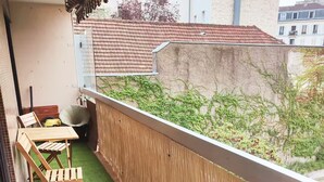 Un balcon avec du gazon synthétique, une chaise en bois et une table.