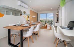 A modern dining area with a wooden table, white chairs, and a laptop on a white desk. - Corporate Stays First Living - 706 (Asunción)