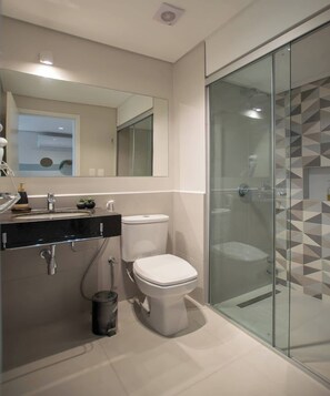 A modern bathroom with a glass shower enclosure, a white toilet, and a black vanity with a mirror. - Corporate Stays First Living - 706 (Asunción)