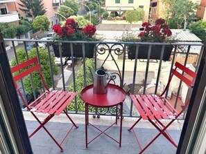 A balcony with two red chairs, a small round table, and a metal kettle. - Panorama Home (Roma)