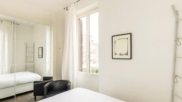 Habitación de hotel con cama, una silla, ventana y un cuadro en la pared.