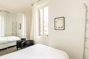 A hotel room with a bed, a chair, a window, and a framed picture on the wall. - Panorama Home (Roma)