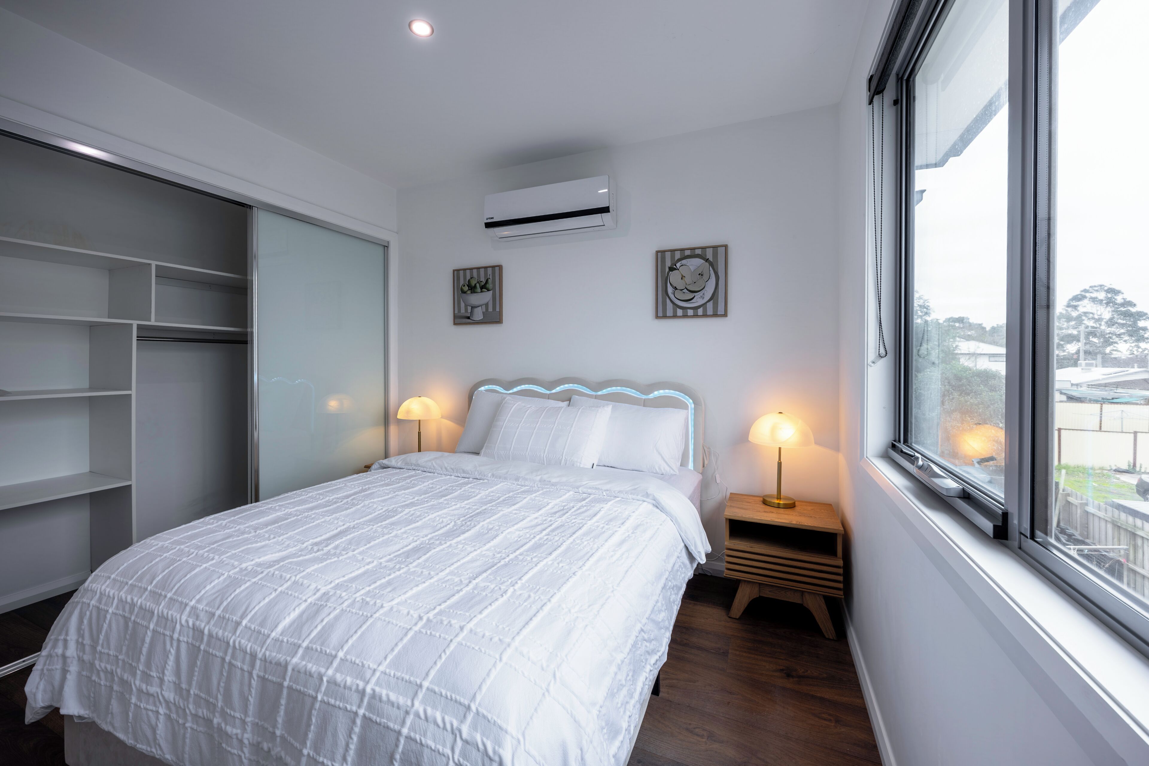 Un dormitorio con cama, mesitas de noche, armario y ventana.