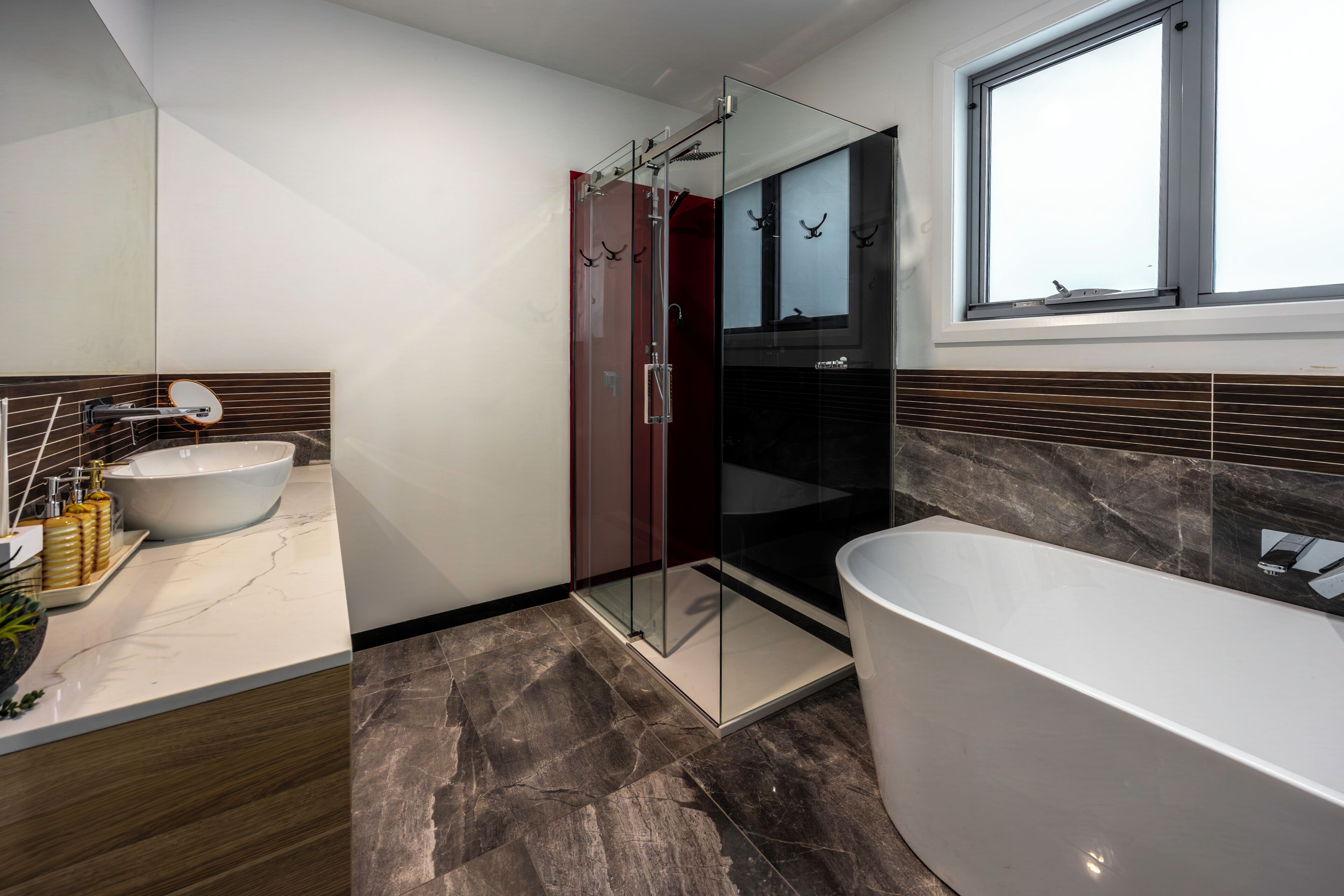 A modern bathroom with a glass-enclosed shower, a freestanding bathtub, and a vanity with a sink.
