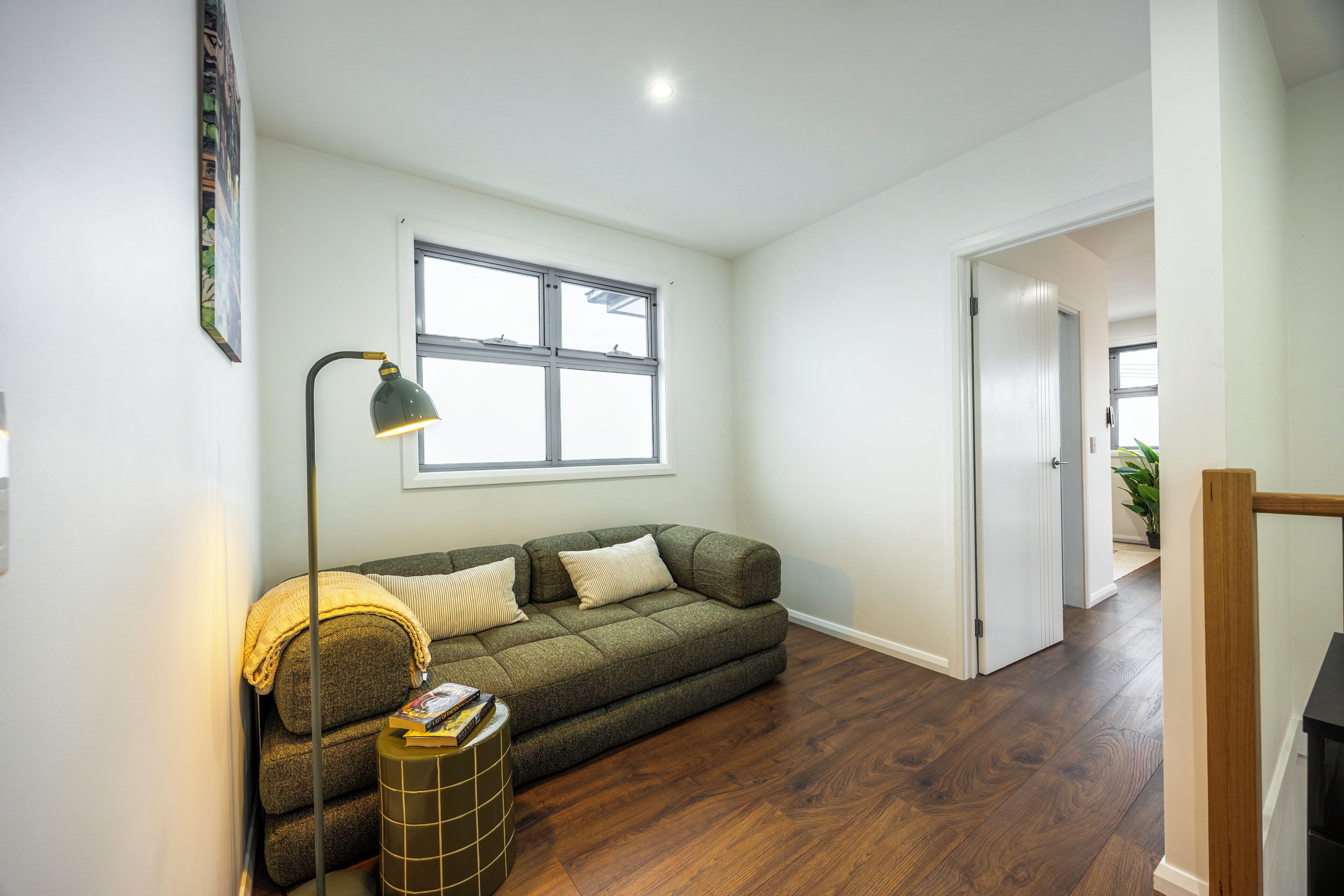A living room with a sofa, a floor lamp, and a window.