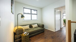 Ein Wohnzimmer mit einer Couch, einer Stehlampe und einem Fenster.