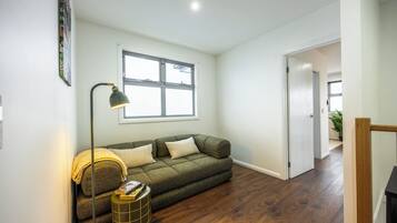 A living room with a sofa, a floor lamp, and a window.