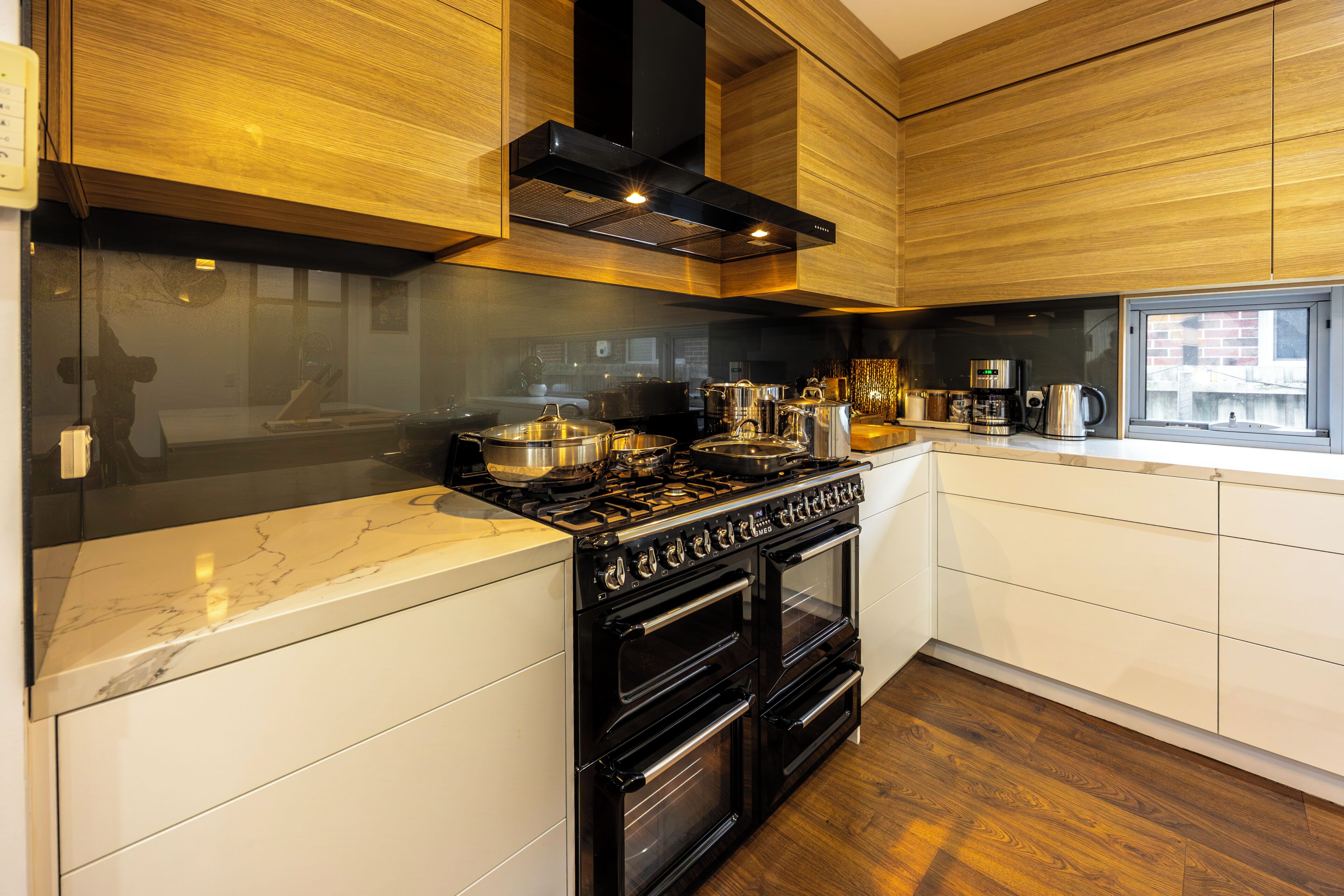 A modern kitchen with a gas stove, oven, and a coffee maker on the counter.