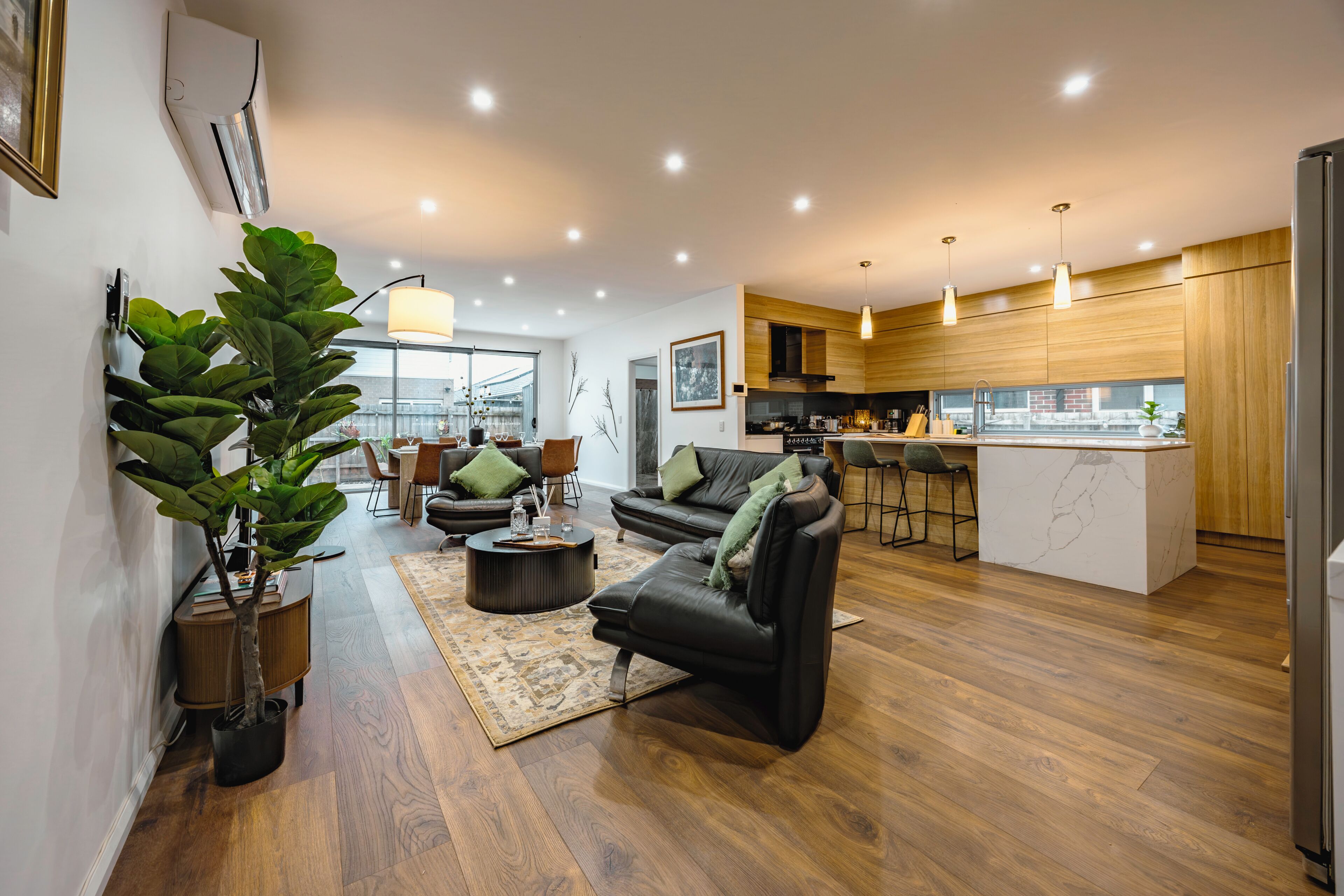 A modern living room with a sofa, coffee table, and a large potted plant.