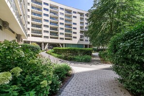 A multi-story building with a paved pathway leading to a gated entrance. - Lumina 3-room Apart with Parking  (Warszawa)