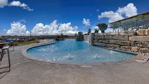 Ein Schwimmbecken mit Steinmauer und Wasserfall.