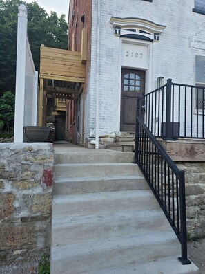 A set of concrete steps leading to a white brick building with a black metal railing. - Over-The-Rhine 4-bedroom 3 bathroom house with off street parking in Cincinnati (Cincinnati)