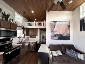 A modern kitchen with a dining area, a wooden ceiling, and a large painting on the wall. - Charming Tiny Home Hideaway with Resort Pool Near Fredericksburg, TX (Fredericksburg)