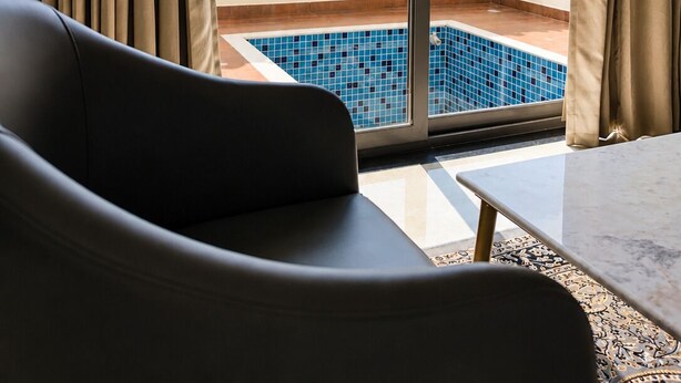 A room with a view of a mountain landscape through a sliding glass door, a pool, and a seating area with a table. - Mijmaan Luxury Villa Udaipur (Udaipur)
