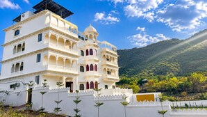 A multi-story building with a white facade, multiple balconies, and a flat roof with solar panels. - Mijmaan Luxury Villa Udaipur (Udaipur)