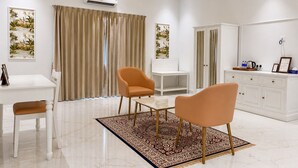 A modern hotel room with a white desk, two chairs, a white cabinet, and a patterned rug. - Mijmaan Luxury Villa Udaipur (Udaipur)