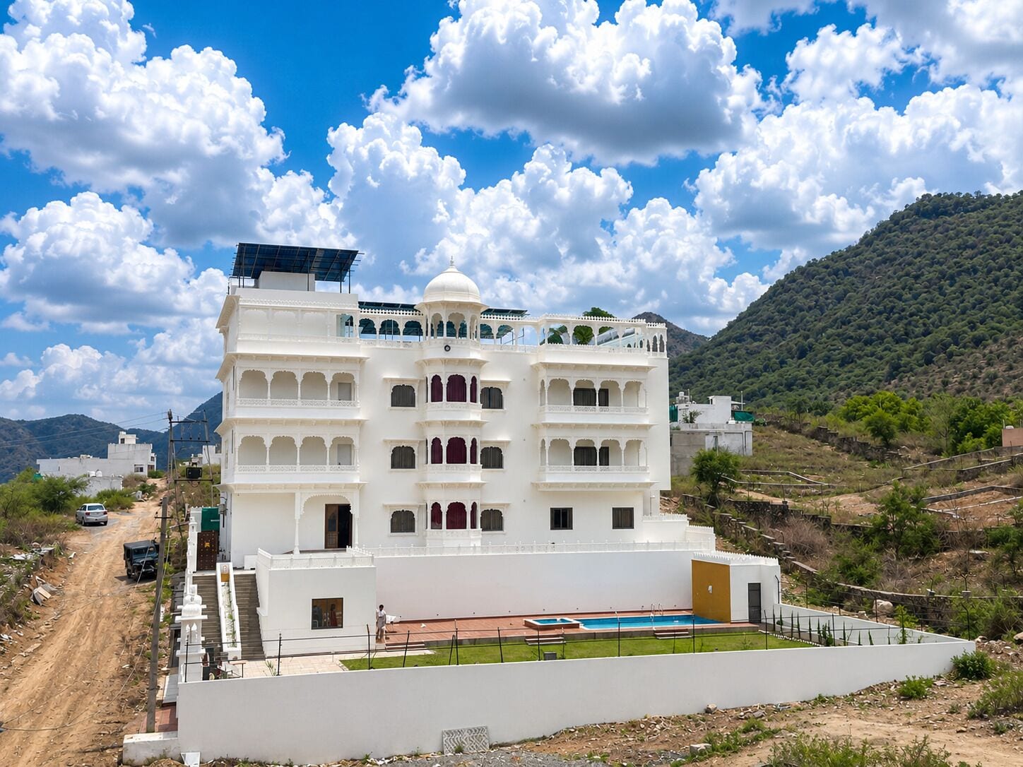 Ein mehrgeschossiges Gebäude mit Flachdach, Swimmingpool und Blick auf eine hügelige Landschaft.