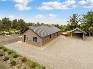 A modern building with a sloped roof, a covered outdoor area, and a gravel driveway.