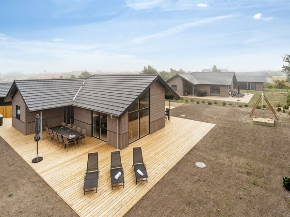 Uma casa moderna com um deck espaçoso, área de refeições e espaço para brincar.