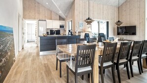 A spacious kitchen with wooden paneling, a dining area with a large table and chairs, and a TV mounted on the wall. - "Merita" - 600m from the sea by Interhome (Thisted)