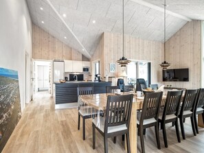 A spacious kitchen with wooden paneling, a dining area with a large table and chairs, and a TV mounted on the wall. - "Merita" - 600m from the sea by Interhome (Thisted)