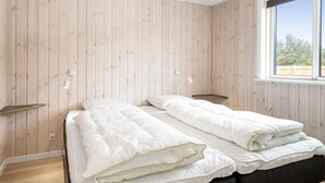 A room with two beds, wooden walls, a window, and bedside lamps. - "Merita" - 600m from the sea by Interhome (Thisted)