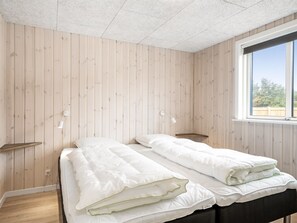 A room with two beds, wooden walls, a window, and bedside lamps. - "Merita" - 600m from the sea by Interhome (Thisted)